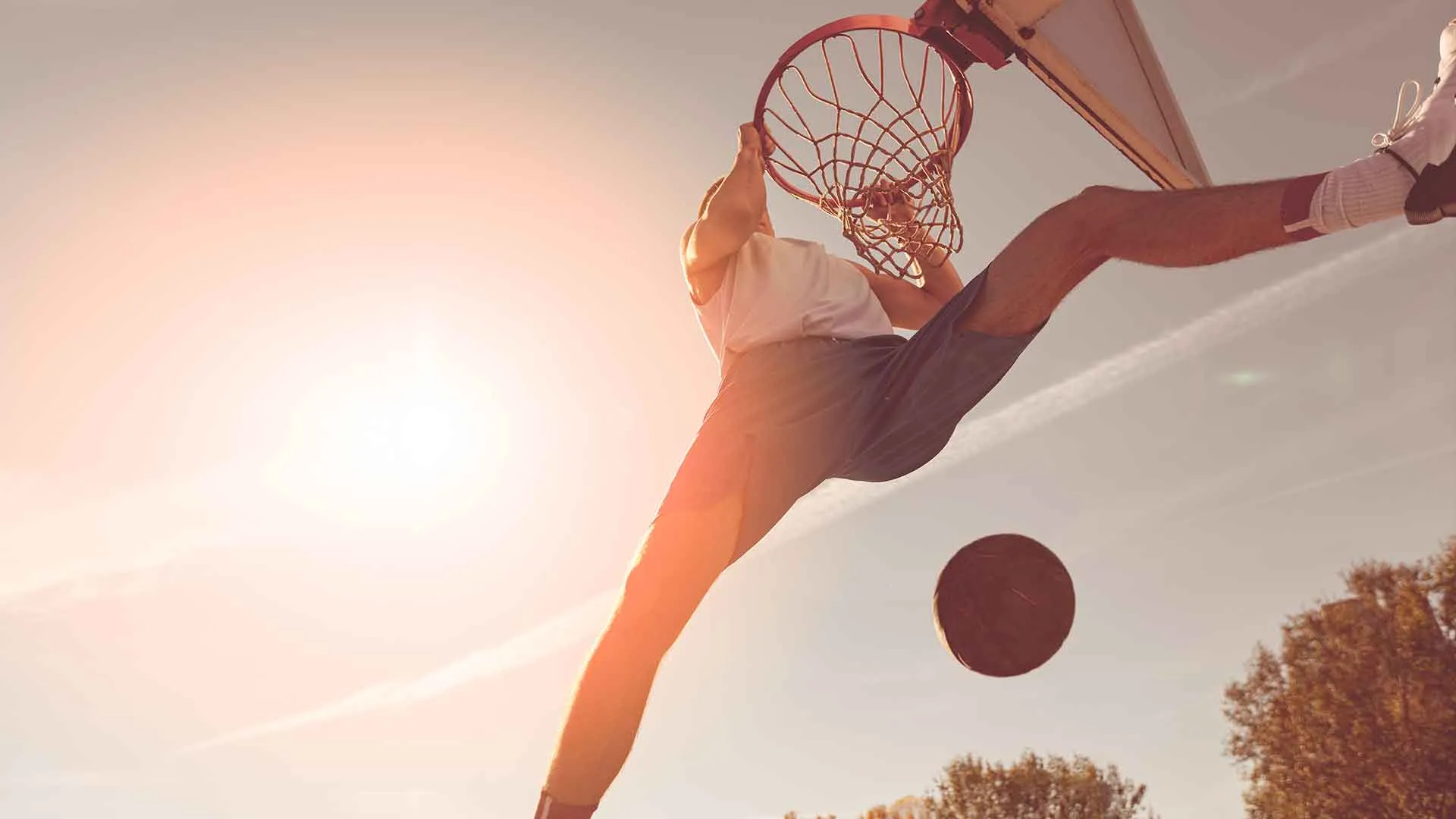 Up view of man basketball dunk under the bright sun